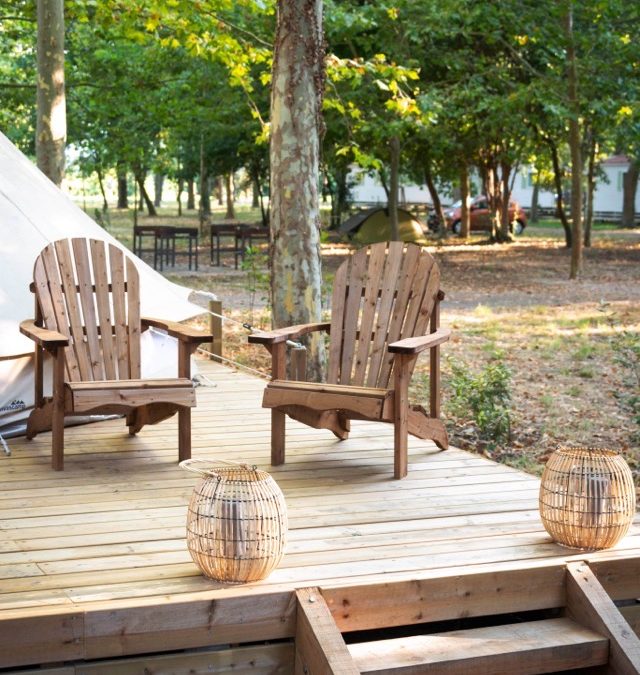 Terrasse avec fauteuils en bois devant une tente safari